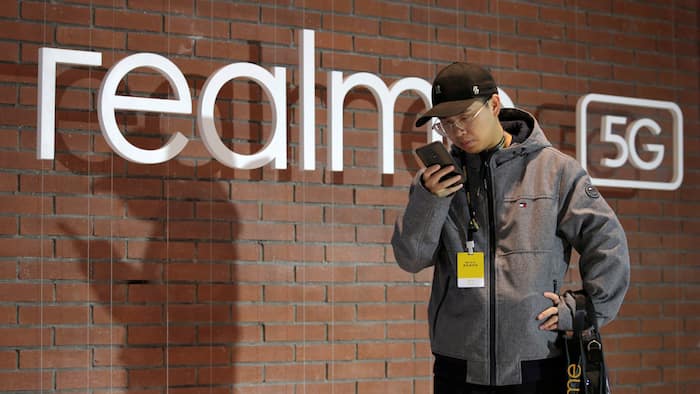 Man looks at mobile phone next to Realme logo during product launch event of X50 5G in Beijing